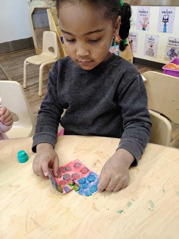 A child creating art with round stamp imprints on paper at a table
