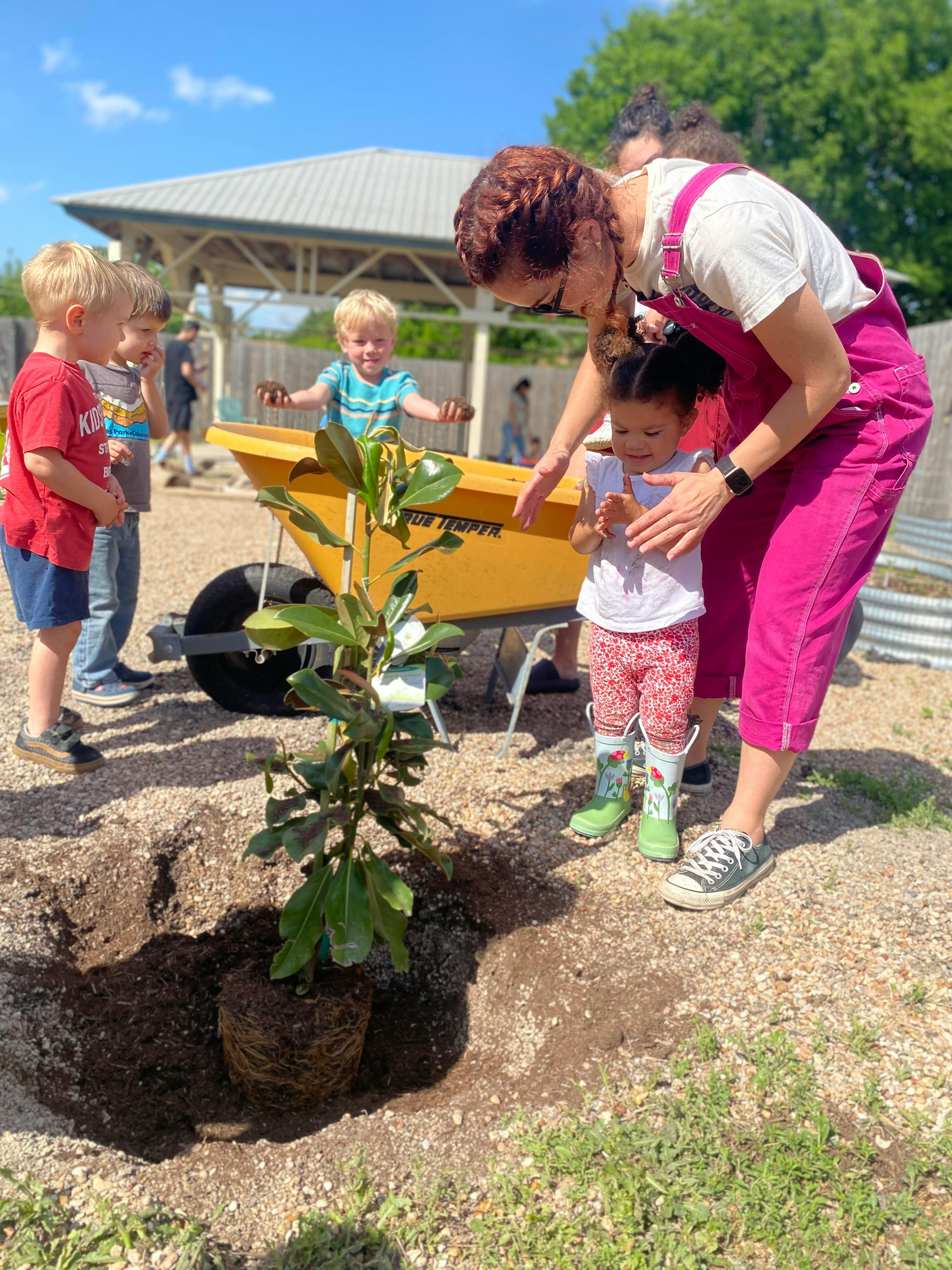 Adult and children planting a tree outdoors
