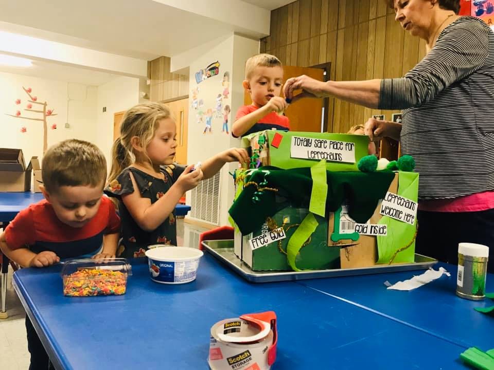 Adult and three children working on a green craft project