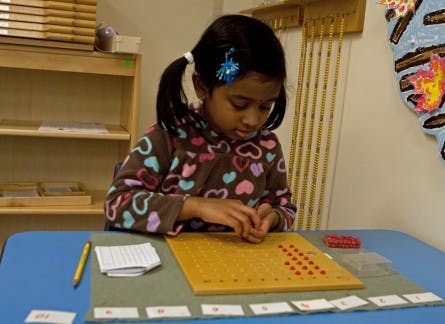Child working with a math counting board and red pegs