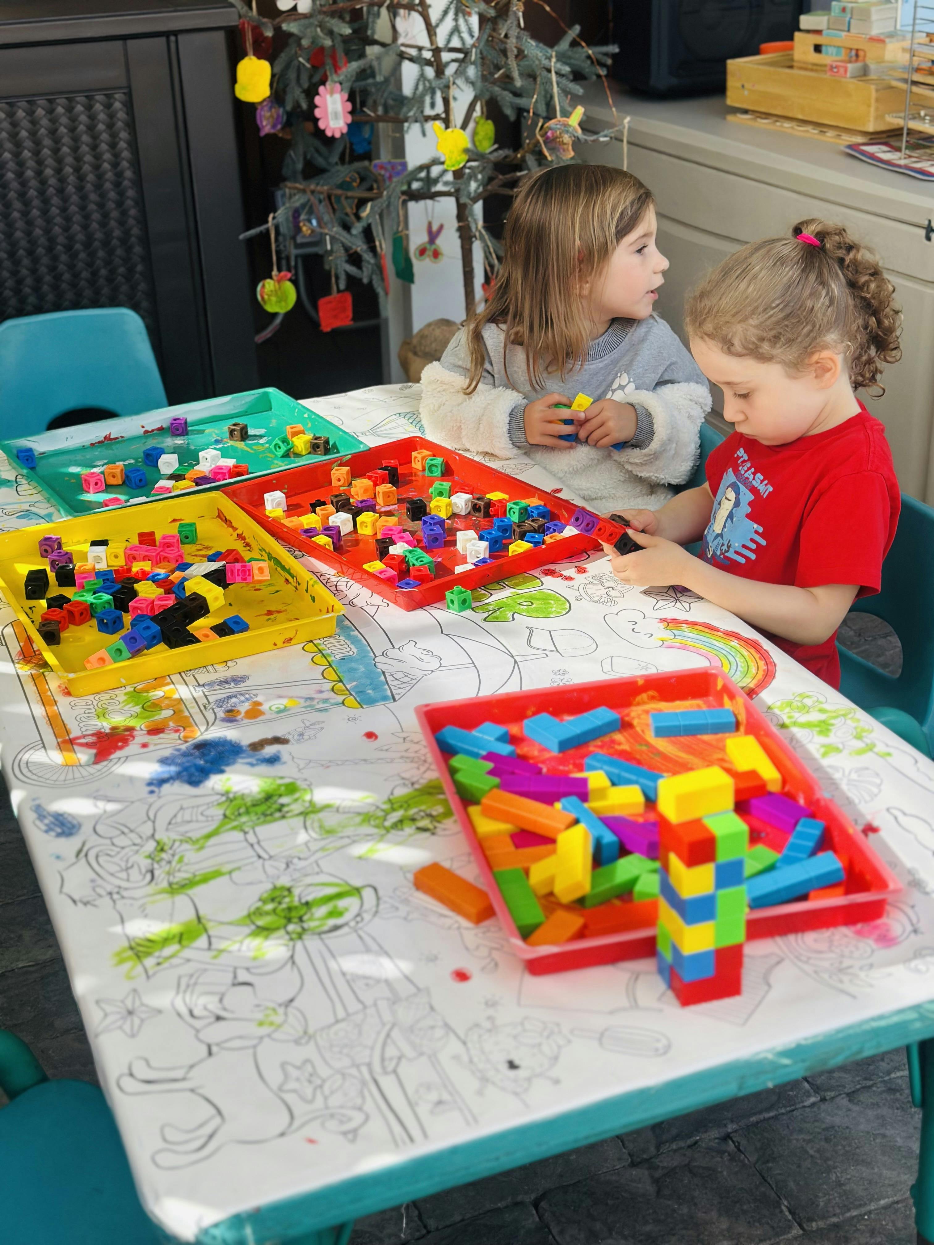 Two children playing with colorful building blocks at a table