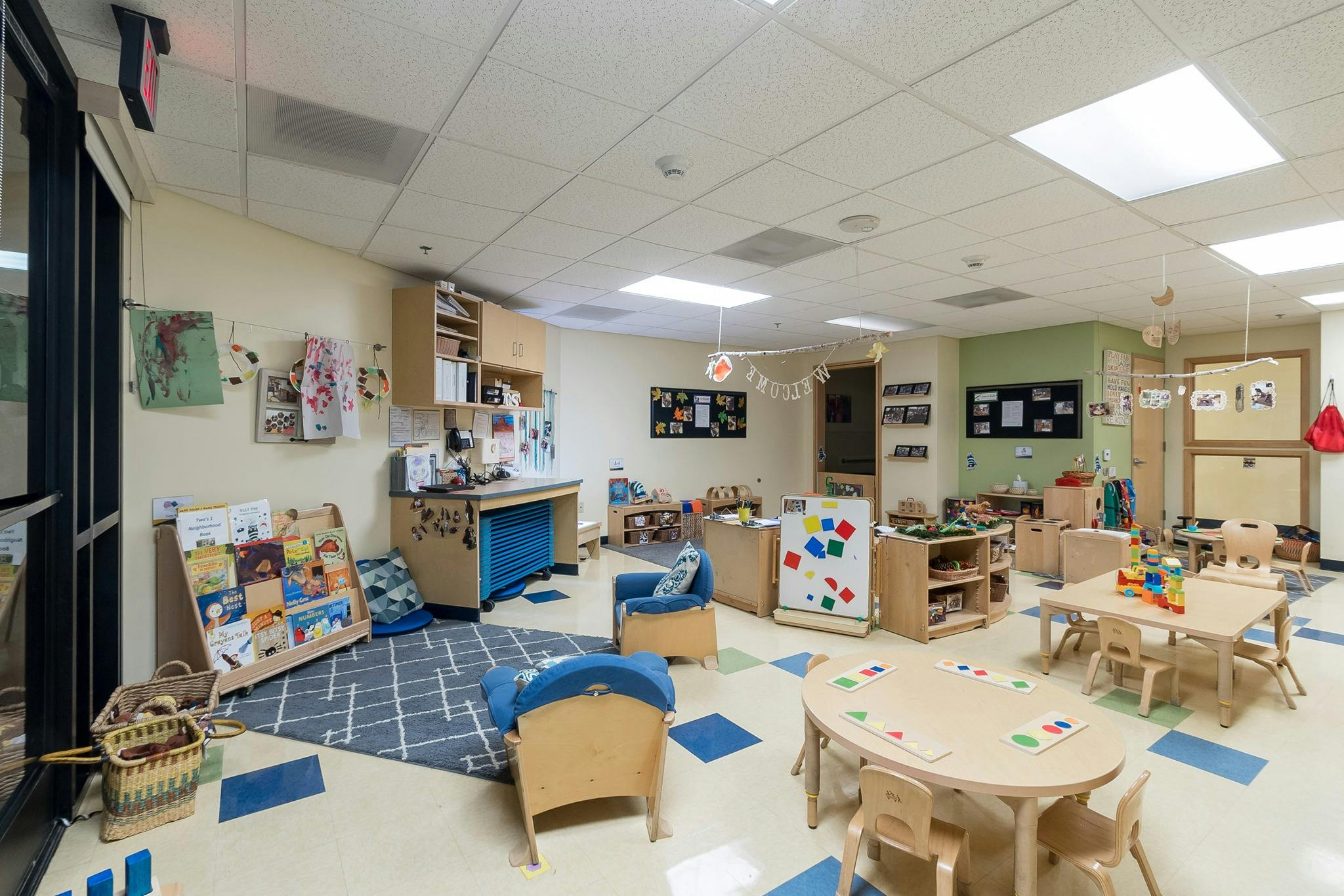Empty classroom with small tables, chairs, and learning materials