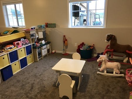 Playroom with toy storage, small table and chairs, and rocking horses