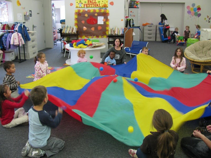 Children playing with a colorful parachute in a classroom