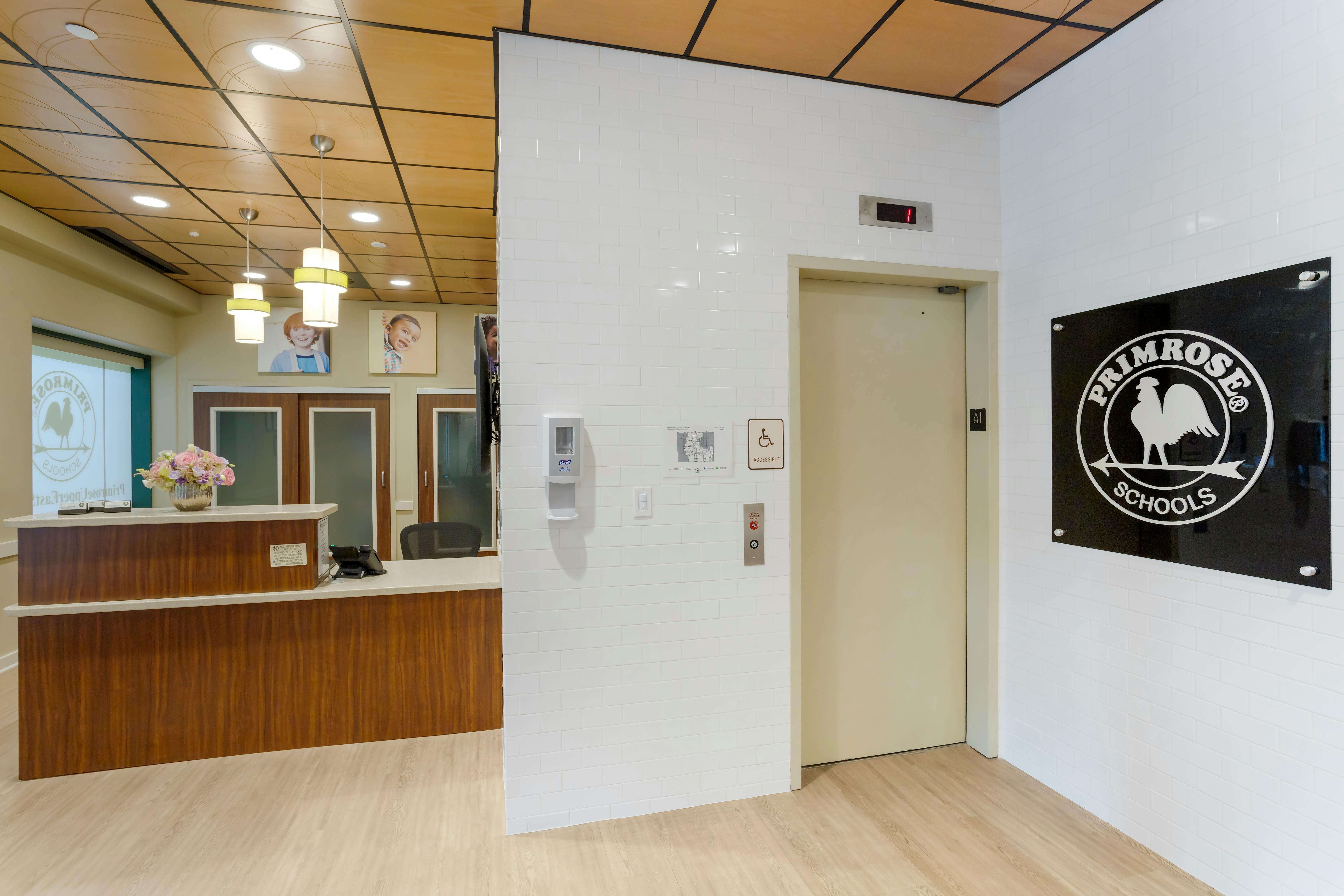 Reception desk with flower arrangement, framed child portraits, and elevator