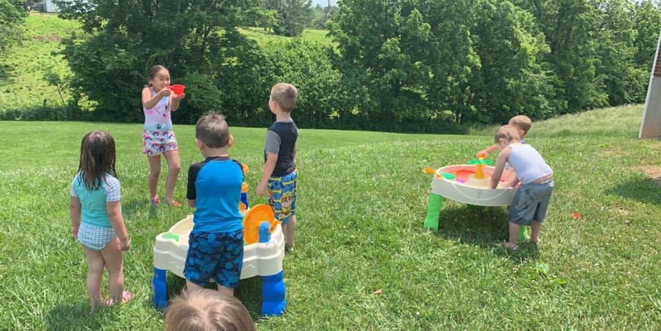 Children playing with water tables outdoors