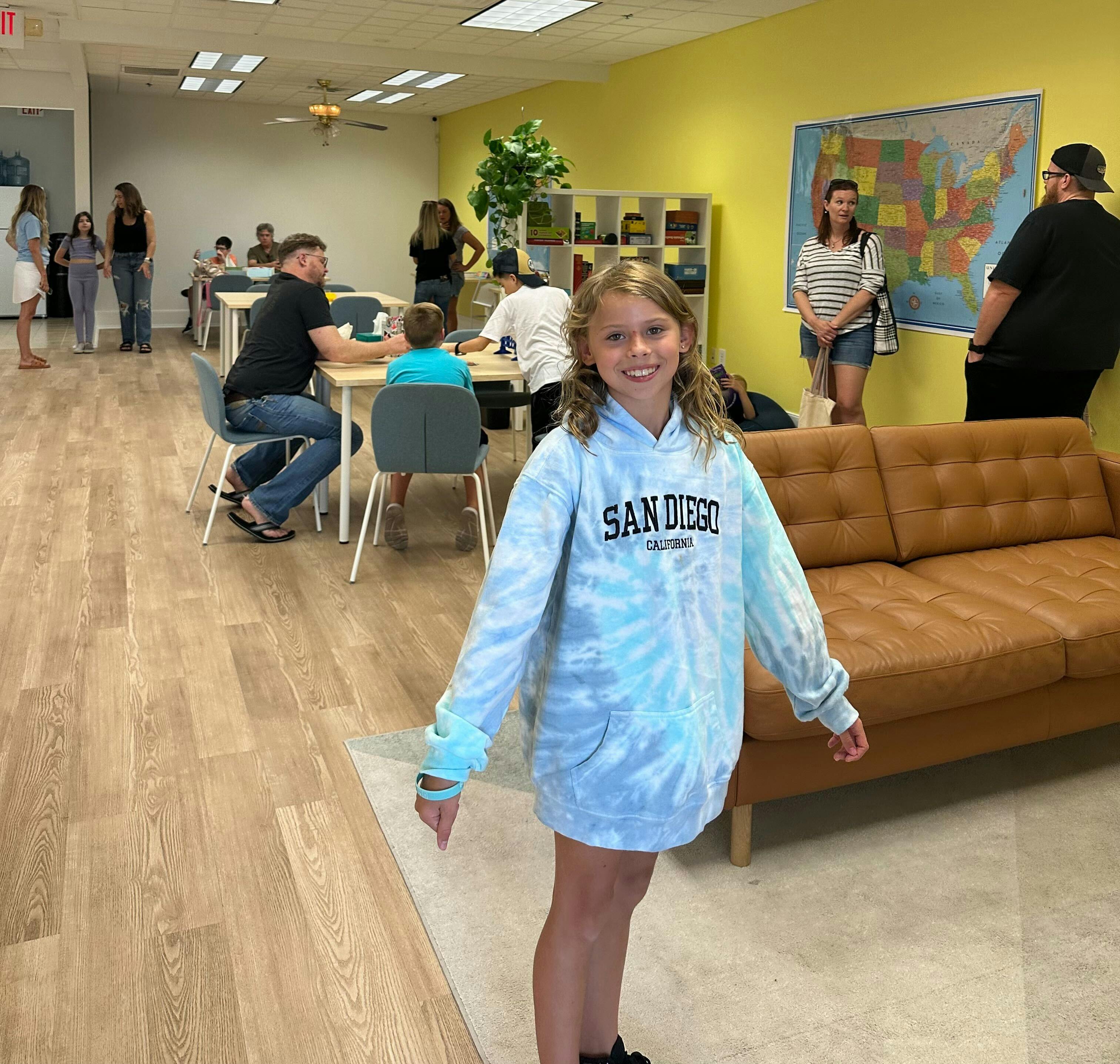 Child in a San Diego sweatshirt standing in a room with other people