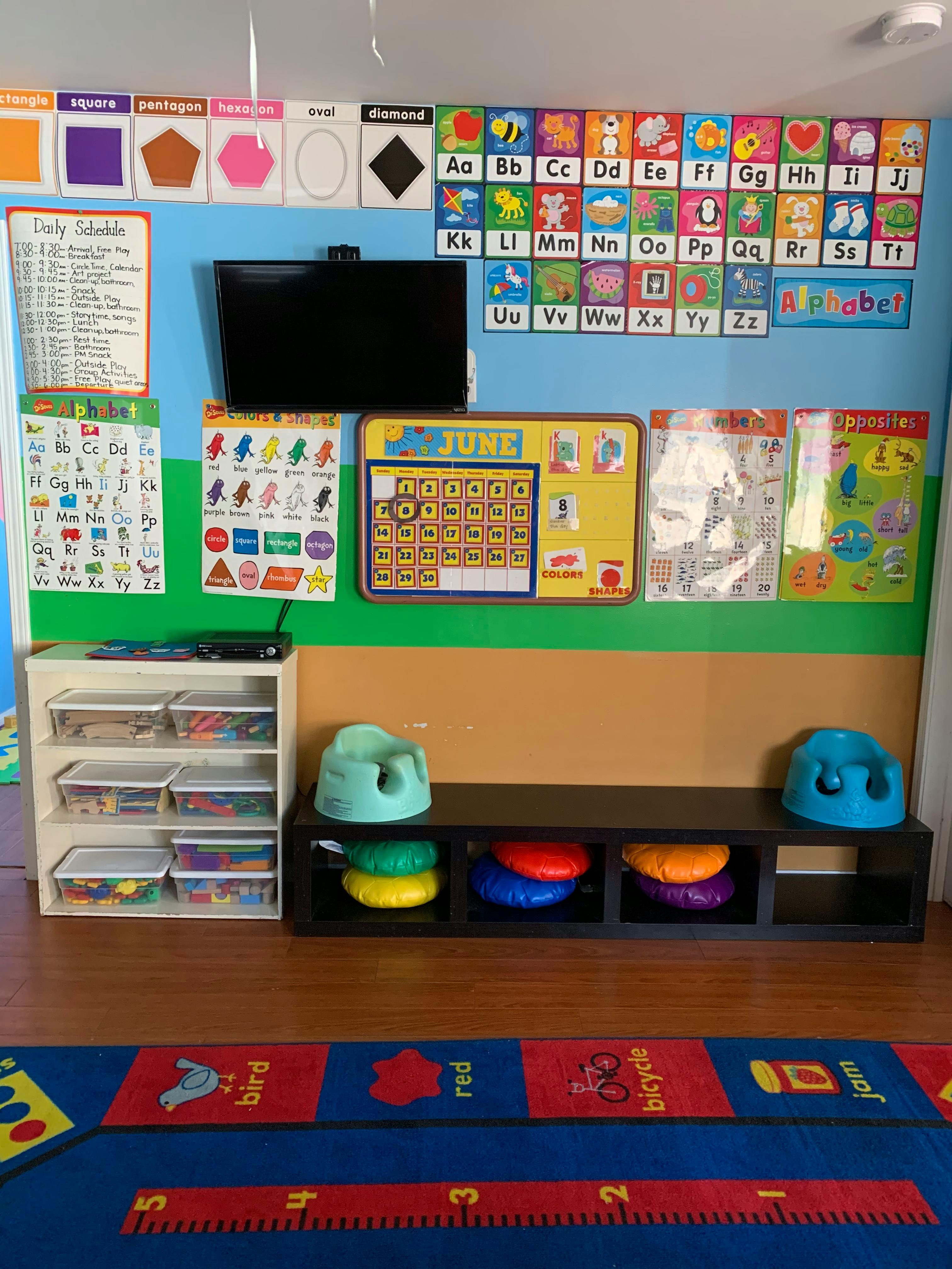 Classroom wall with alphabet charts, calendar, and a television