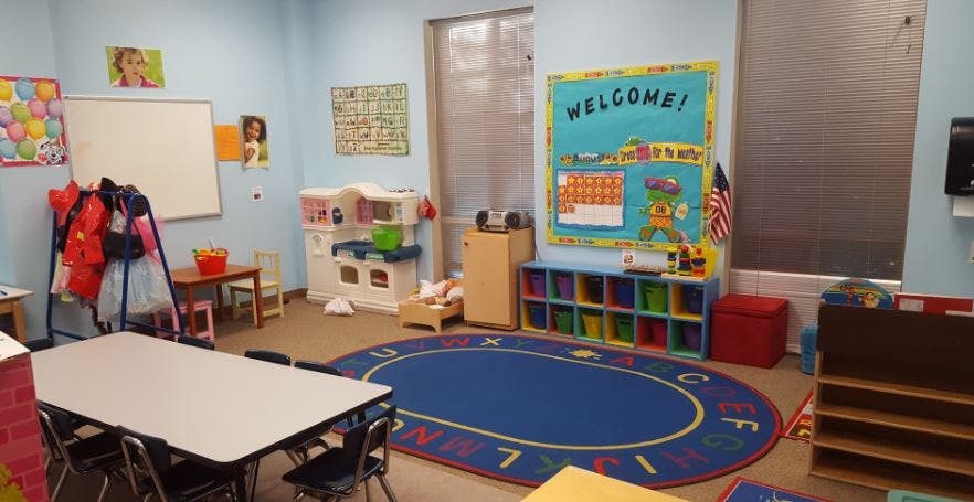 Classroom with tables, chairs, and a blue oval rug