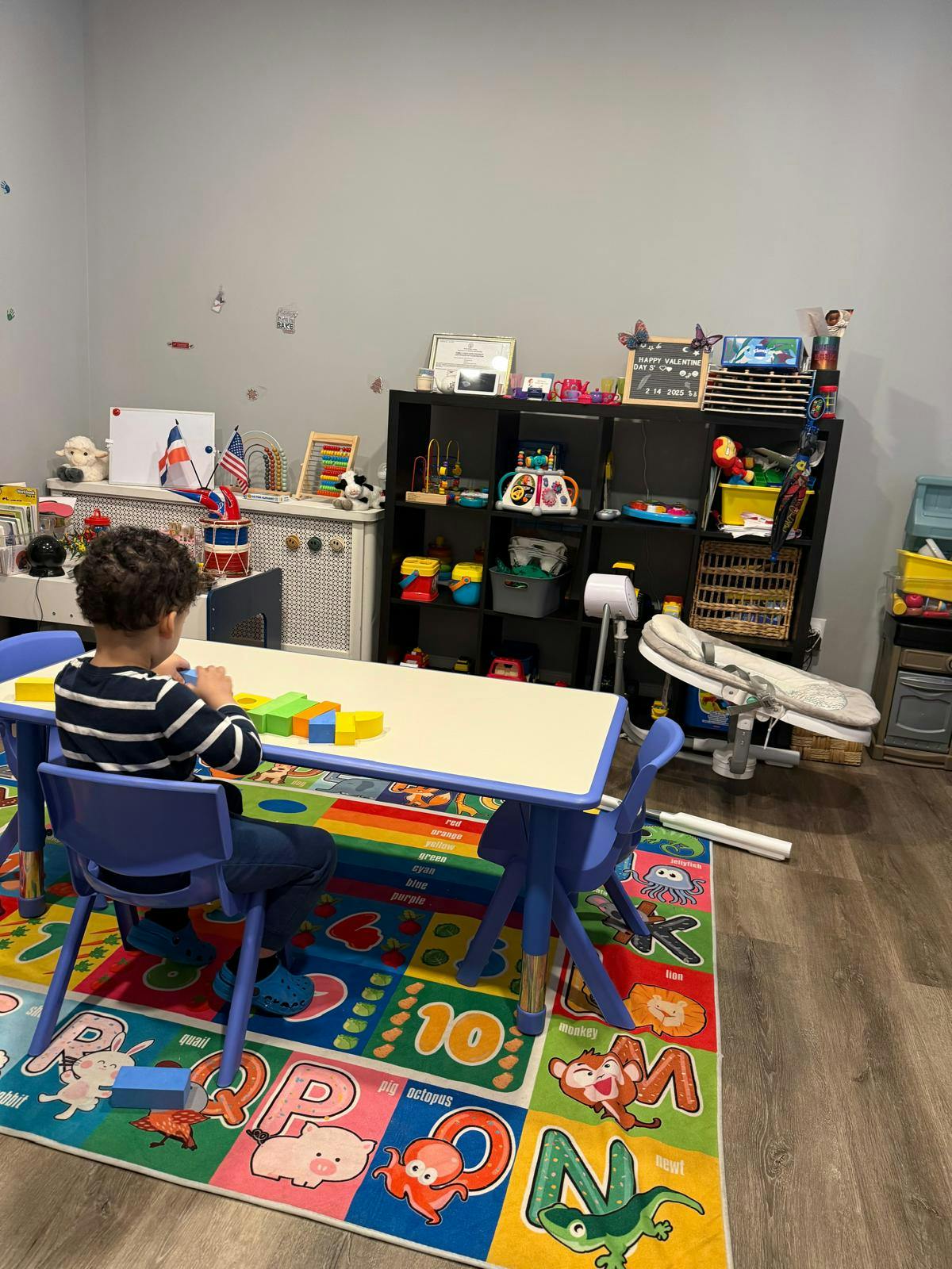 Child playing with blocks at a table in a room with toys
