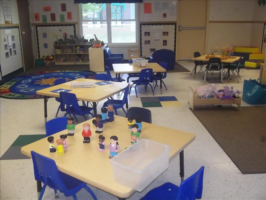 Classroom with small tables and chairs, toys on tables and shelves