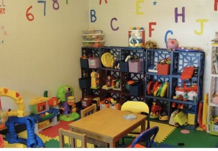 Playroom with toys, shelves, small table, and alphabet letters on the wall