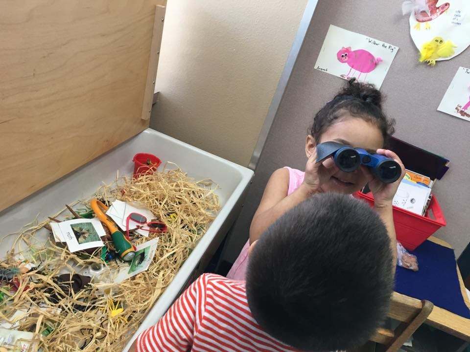 Child looking through binoculars, another child in foreground