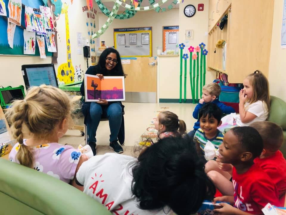 Person reading a book to a group of children in a classroom
