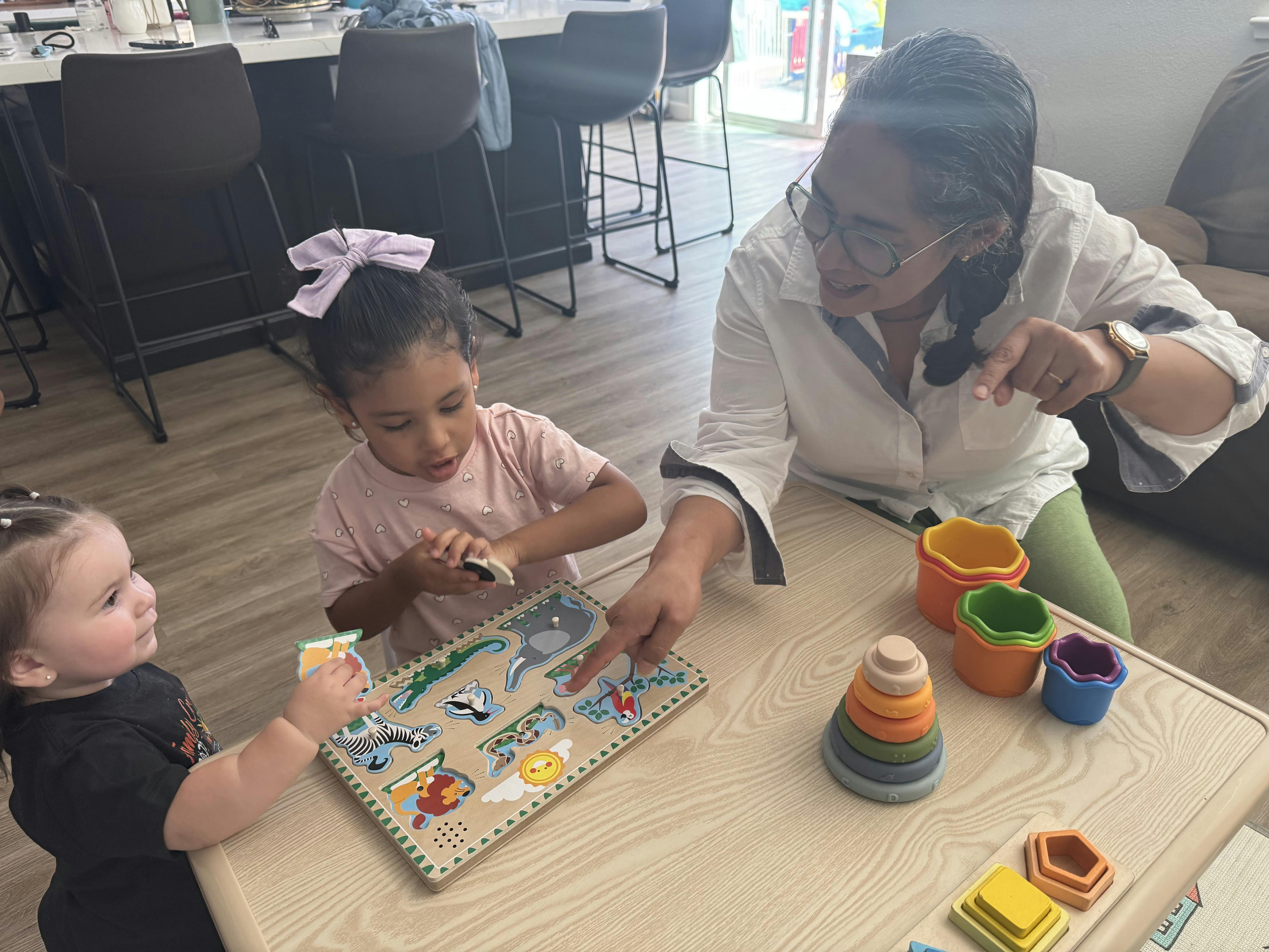 Adult and two children playing with an animal puzzle at a table