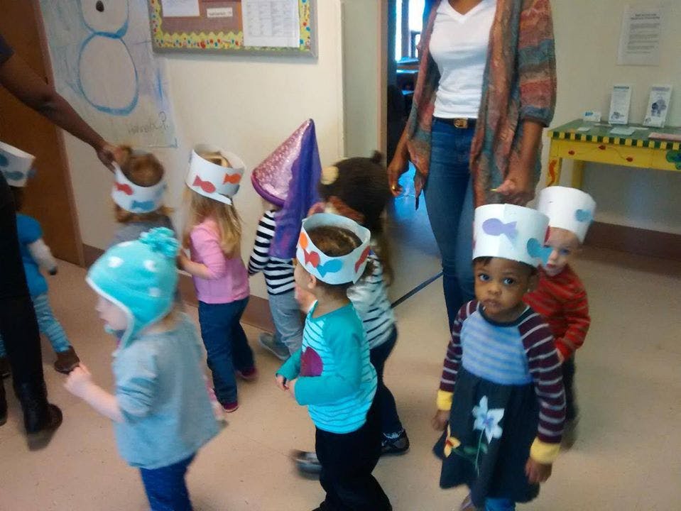 Children wearing paper crowns in a classroom with an adult