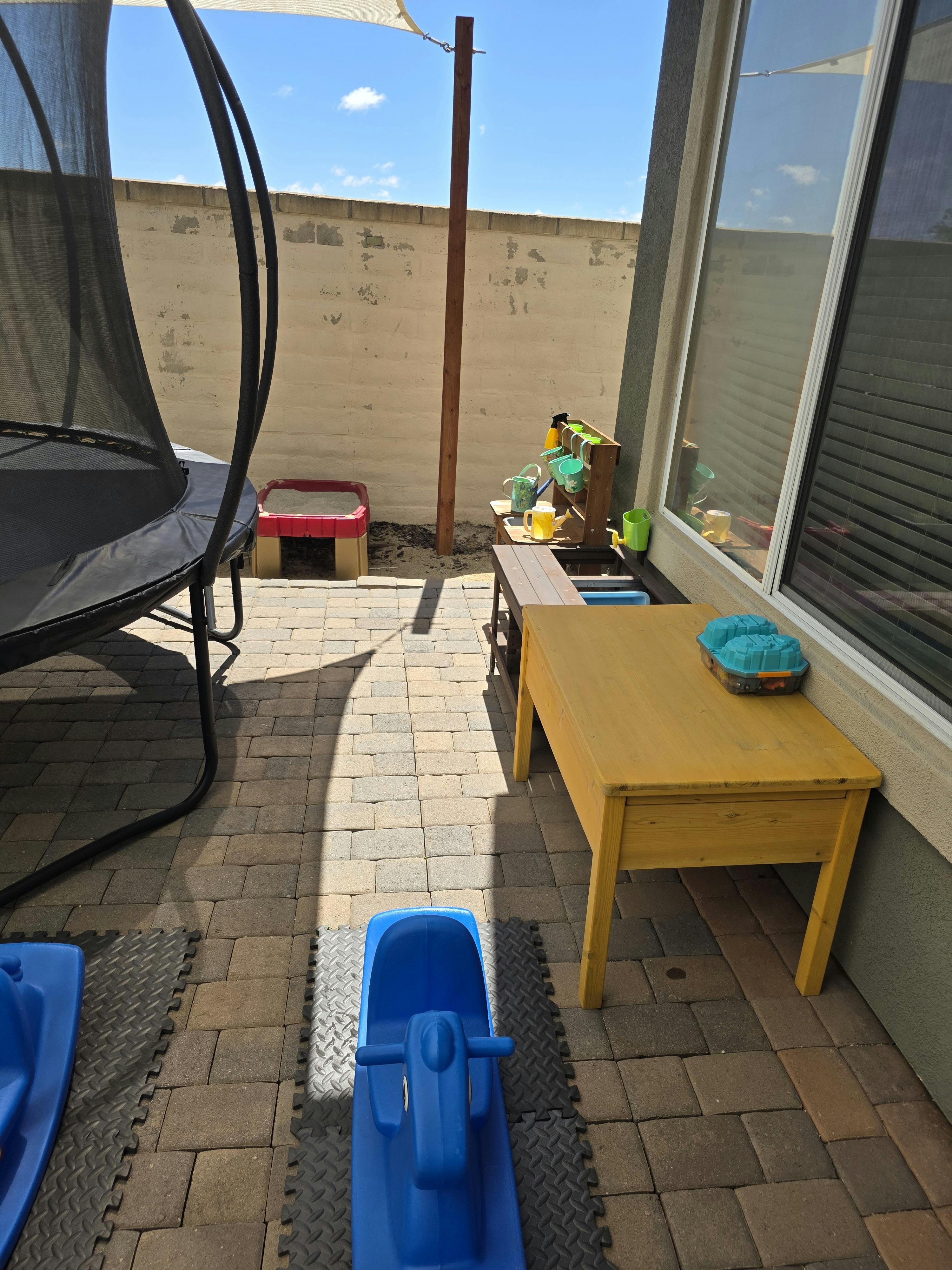 Children's play area with a trampoline, sandbox, and mud kitchen