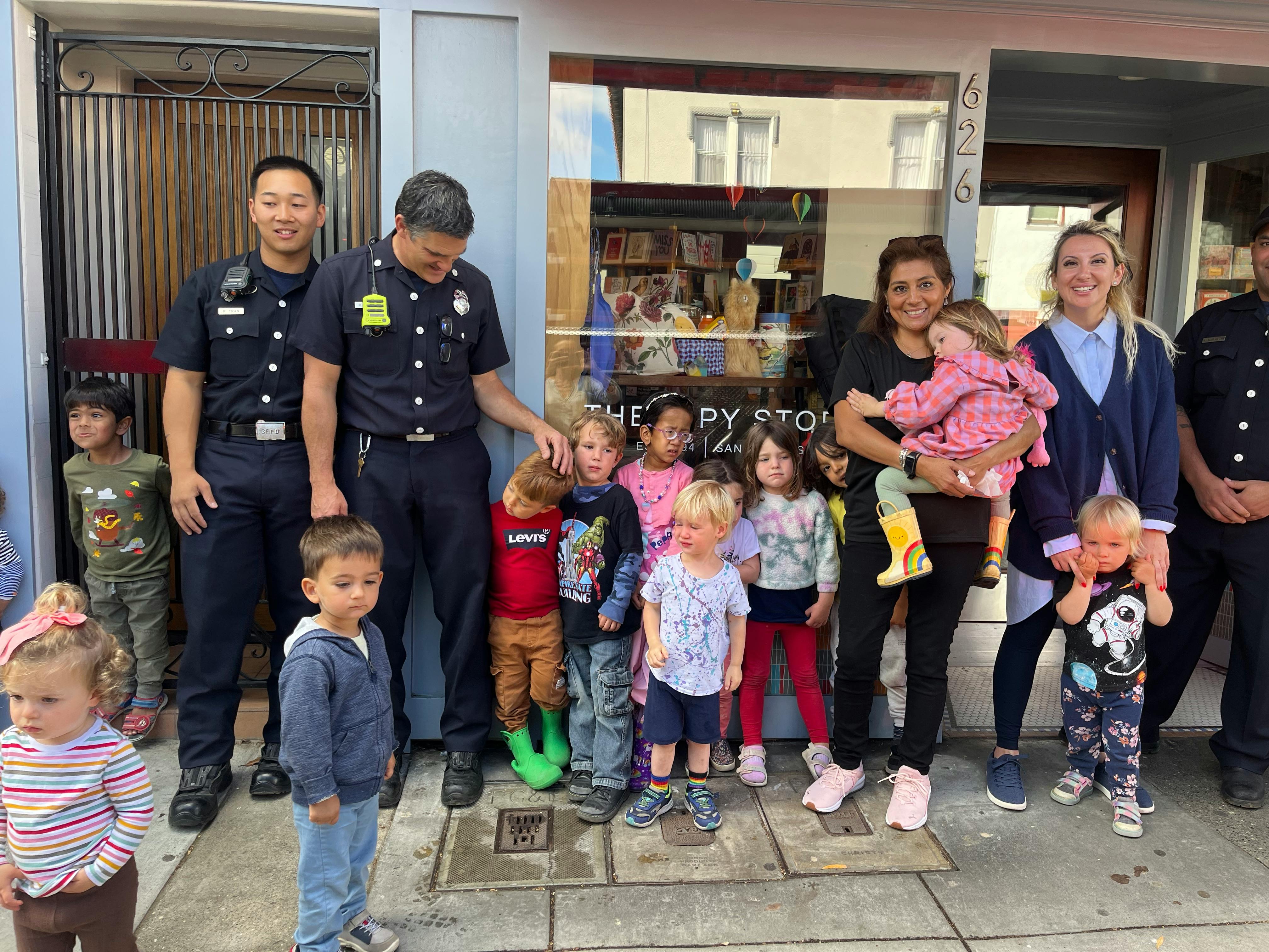 Two people in uniform with adults and children standing outside a building