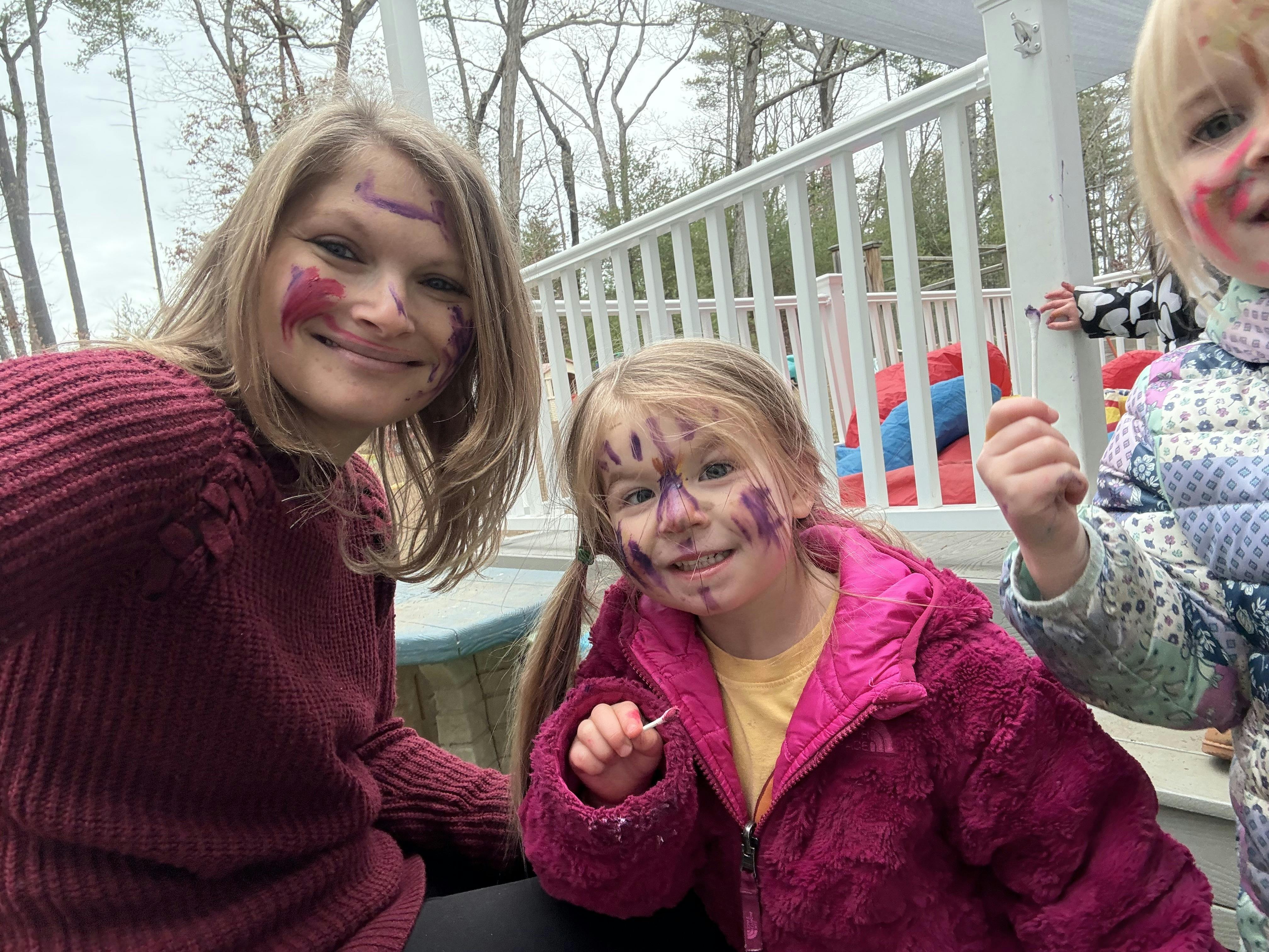 A person and two children with face paint on outdoor deck