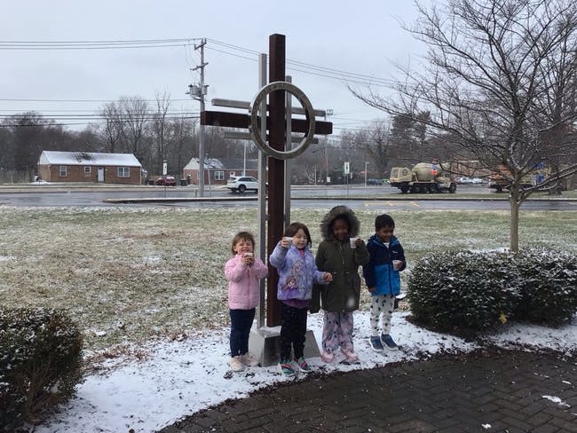 Four children standing outside in snow, holding cups