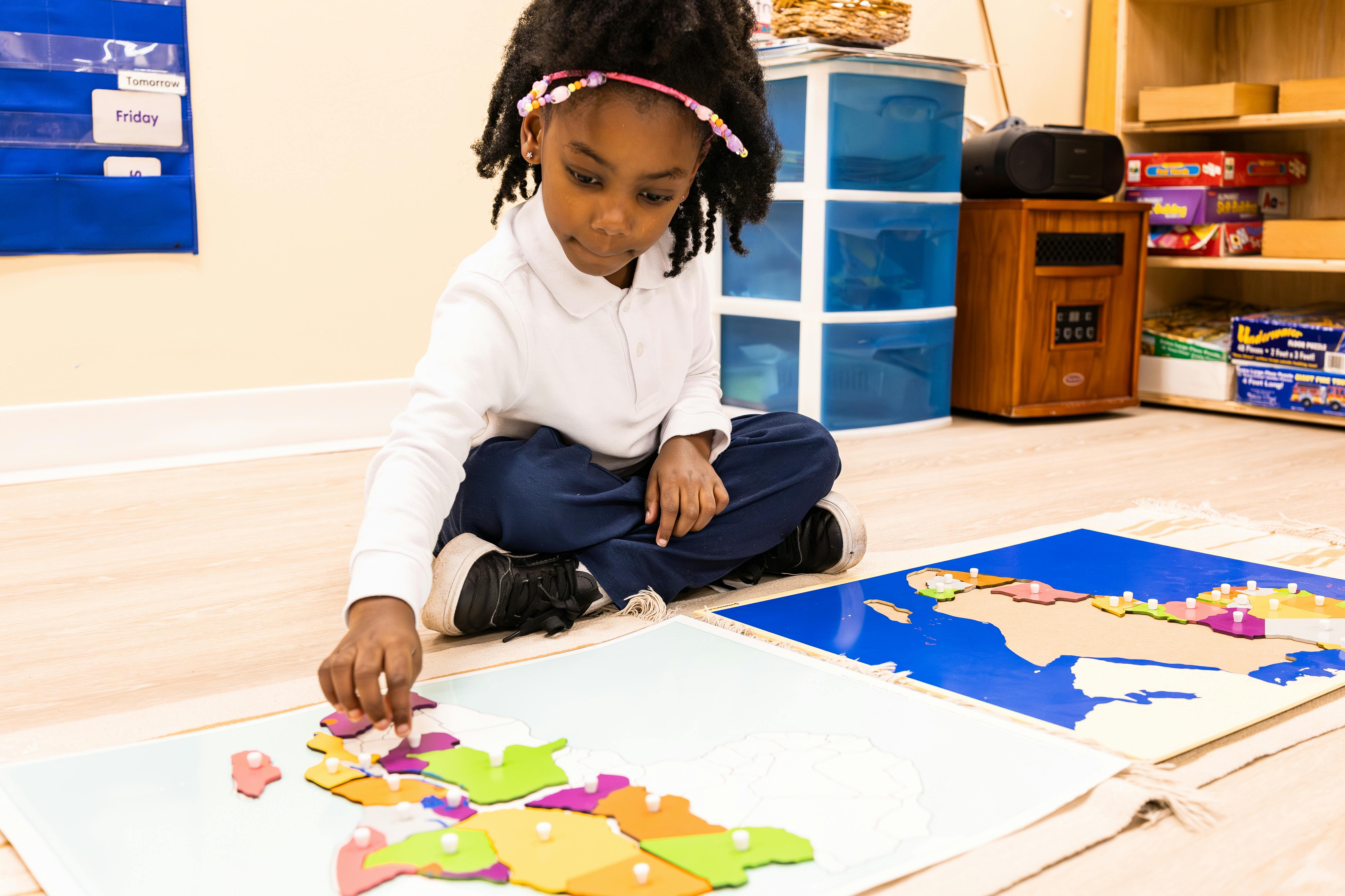 Child sitting on the floor assembling a world map puzzle