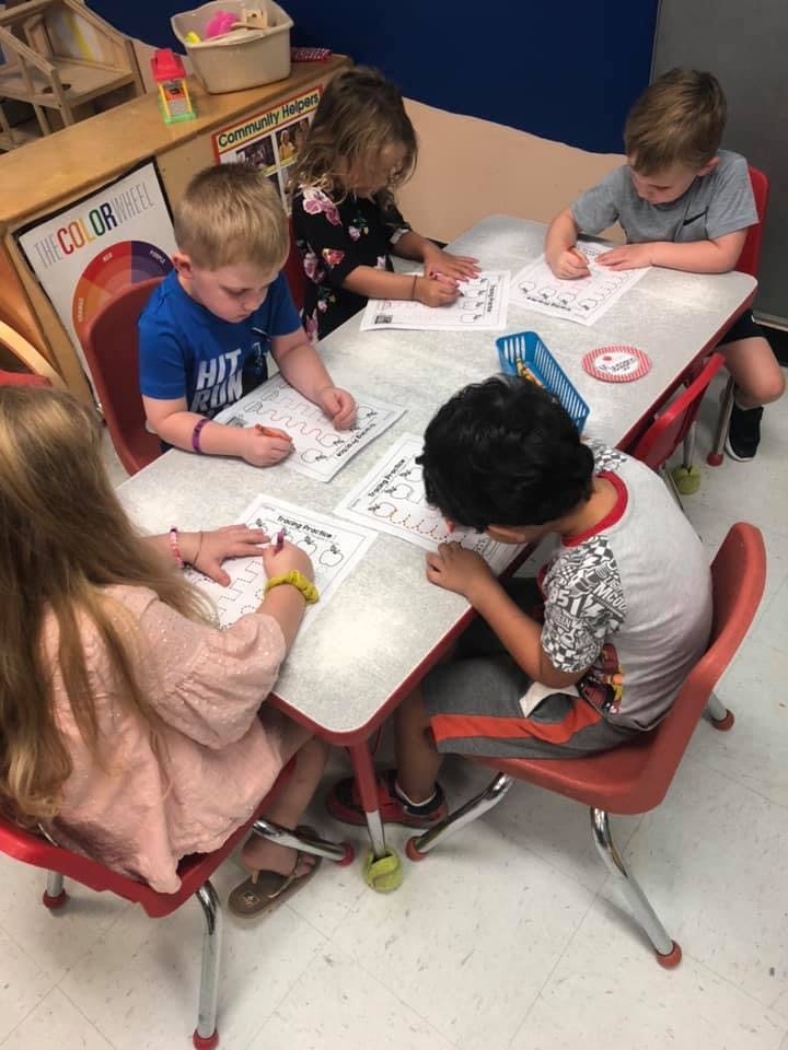 Four children sitting at a table doing schoolwork