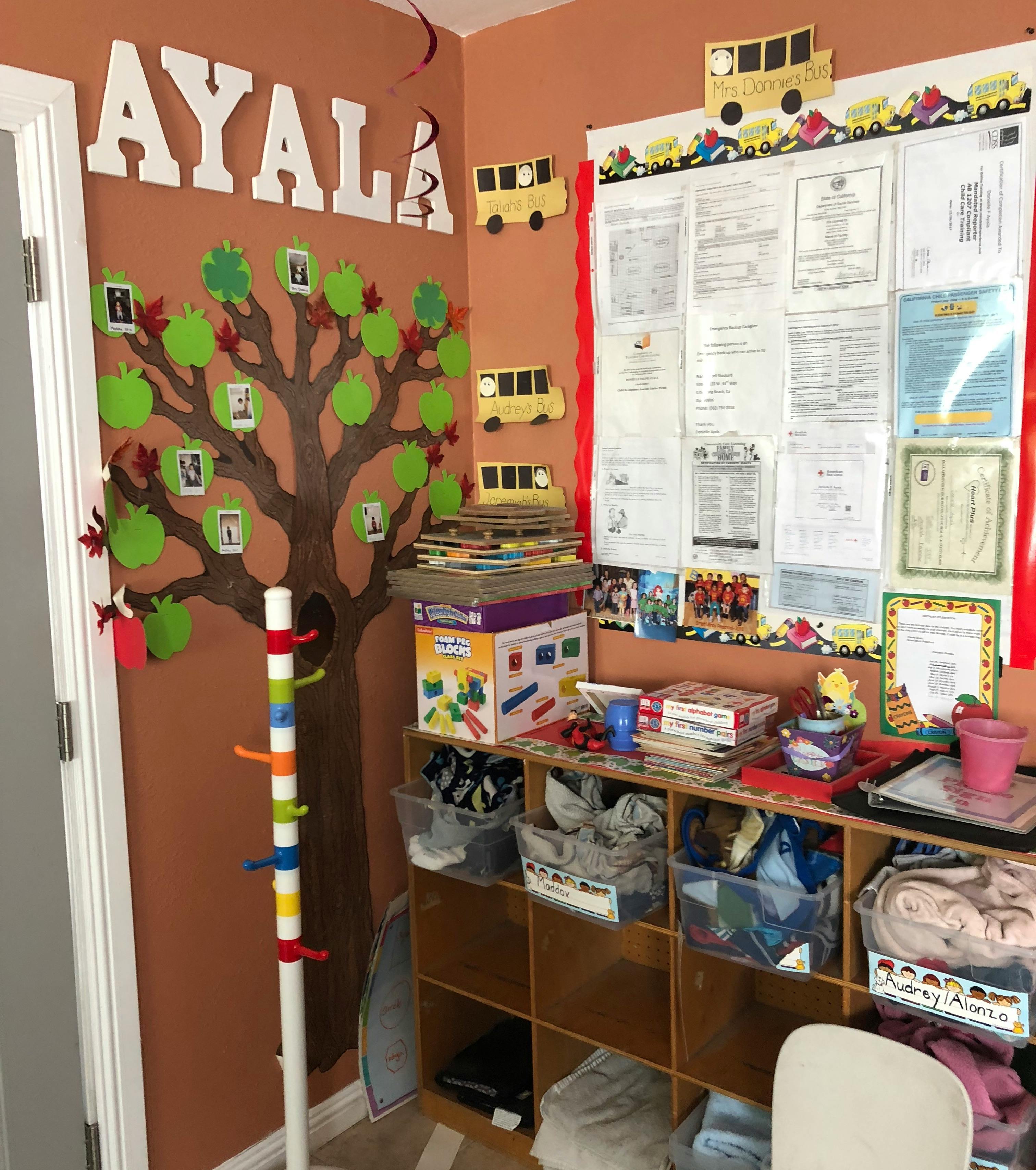 Classroom wall with a tree mural, the name AYALA, and a bulletin board