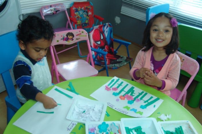 Two children doing crafts at a green table