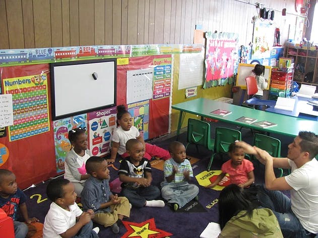 Adult teaching a group of children sitting on the floor in a classroom