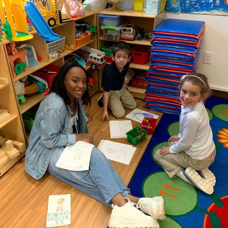 Adult and two children sitting on floor with papers in a classroom
