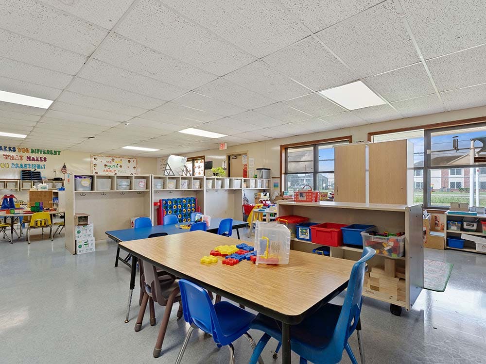 Classroom with small tables and chairs, storage cubbies, and windows