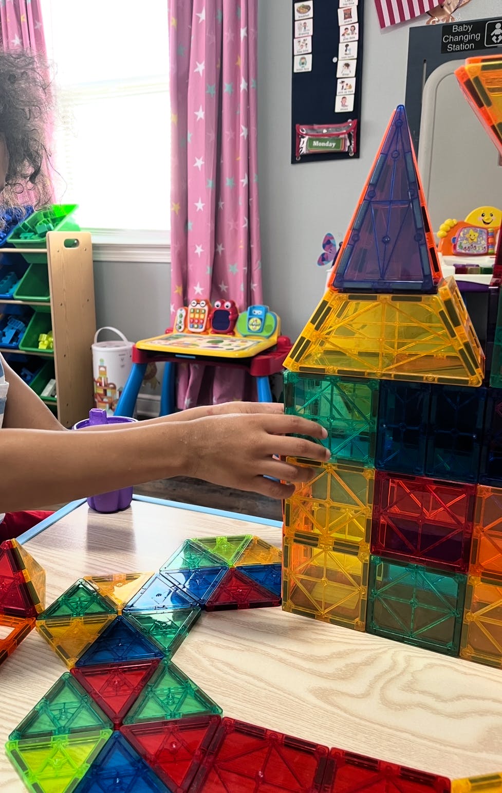 Person building a structure with colorful magnetic tiles
