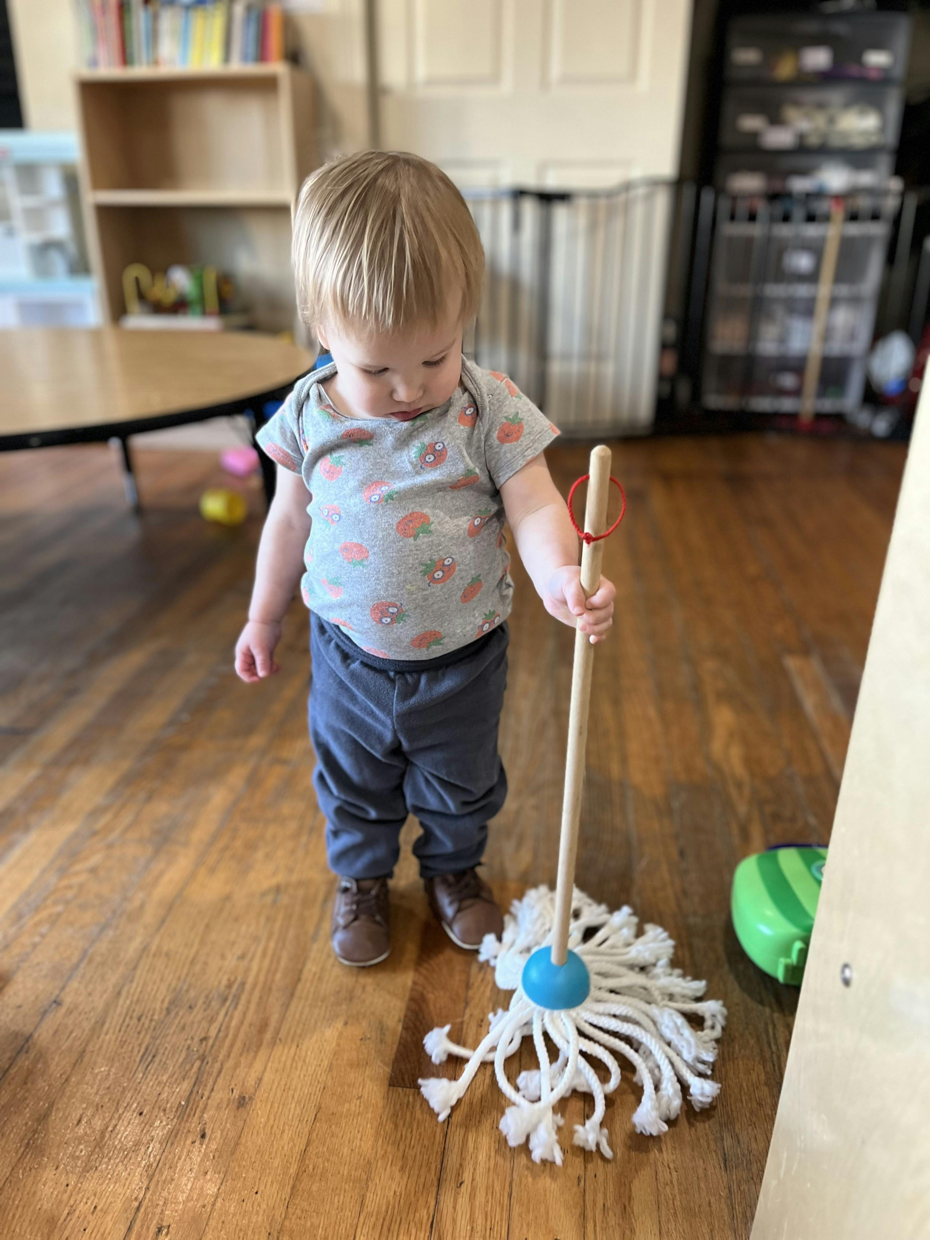 Child holding a toy mop