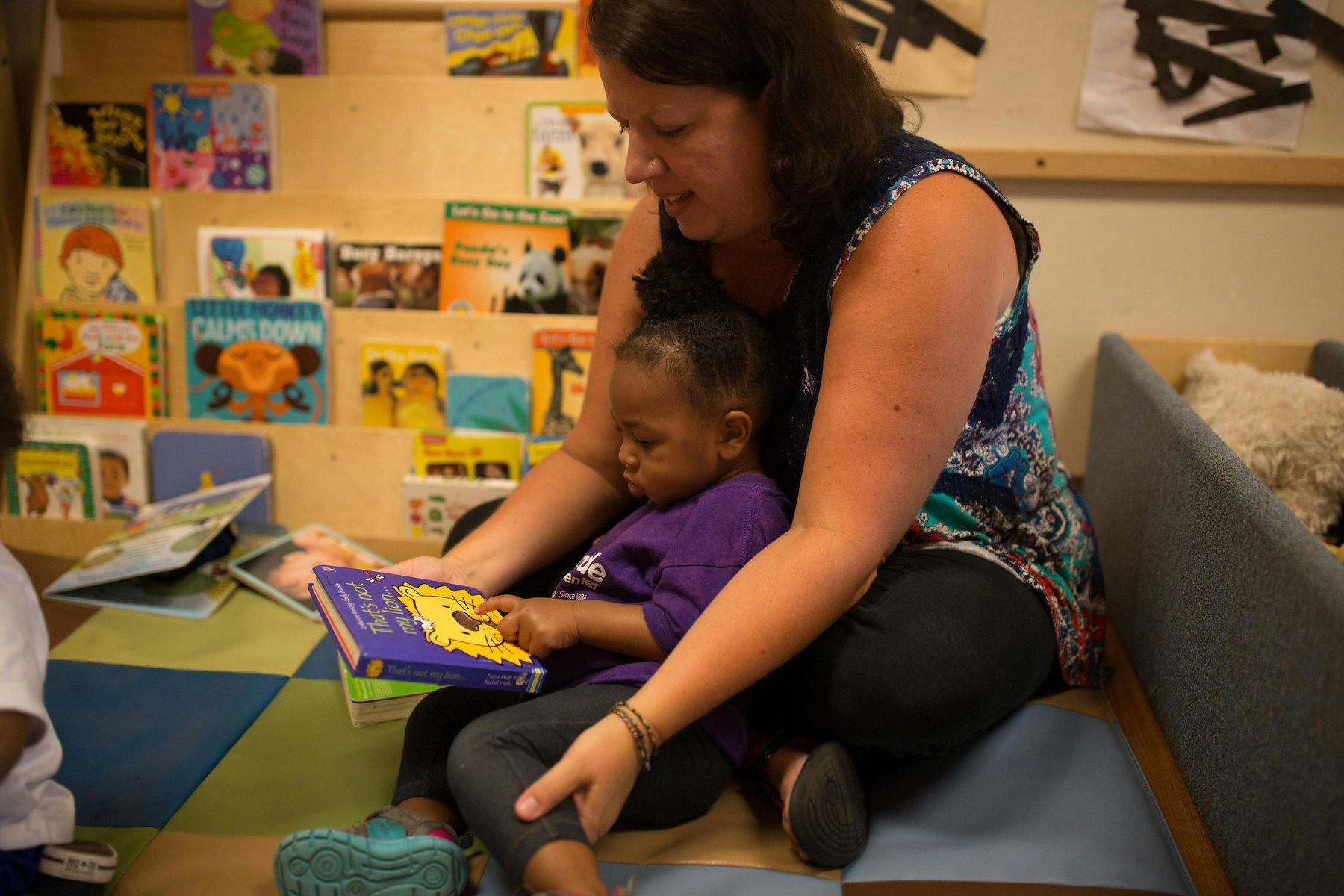 Adult and child sitting on the floor reading a book together