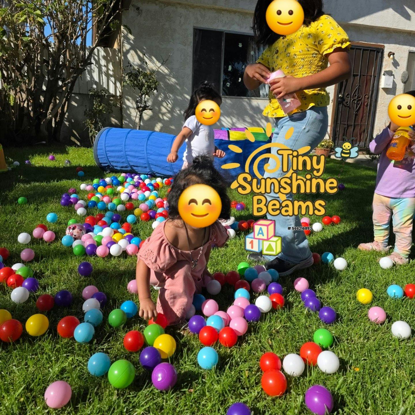 Children playing in a yard filled with colorful plastic balls