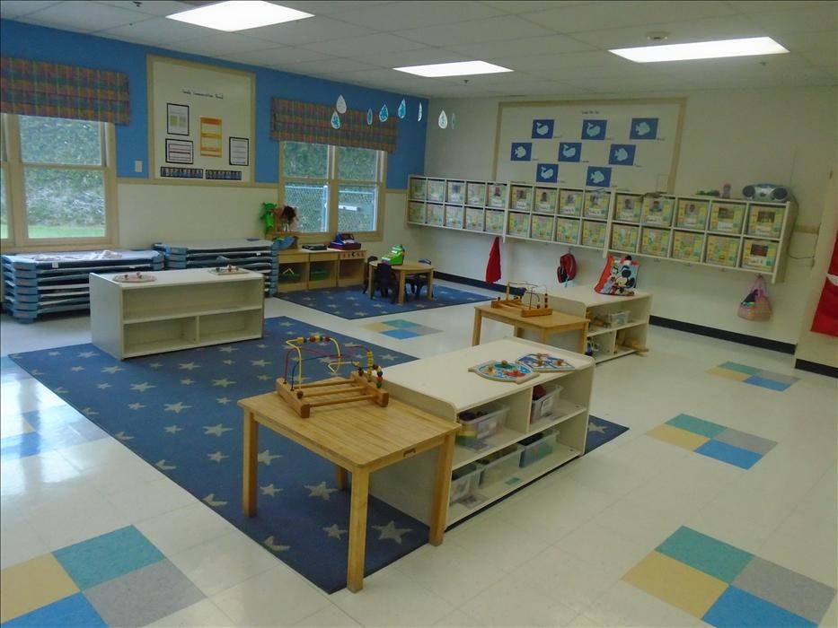An empty classroom with small tables, chairs, and learning materials