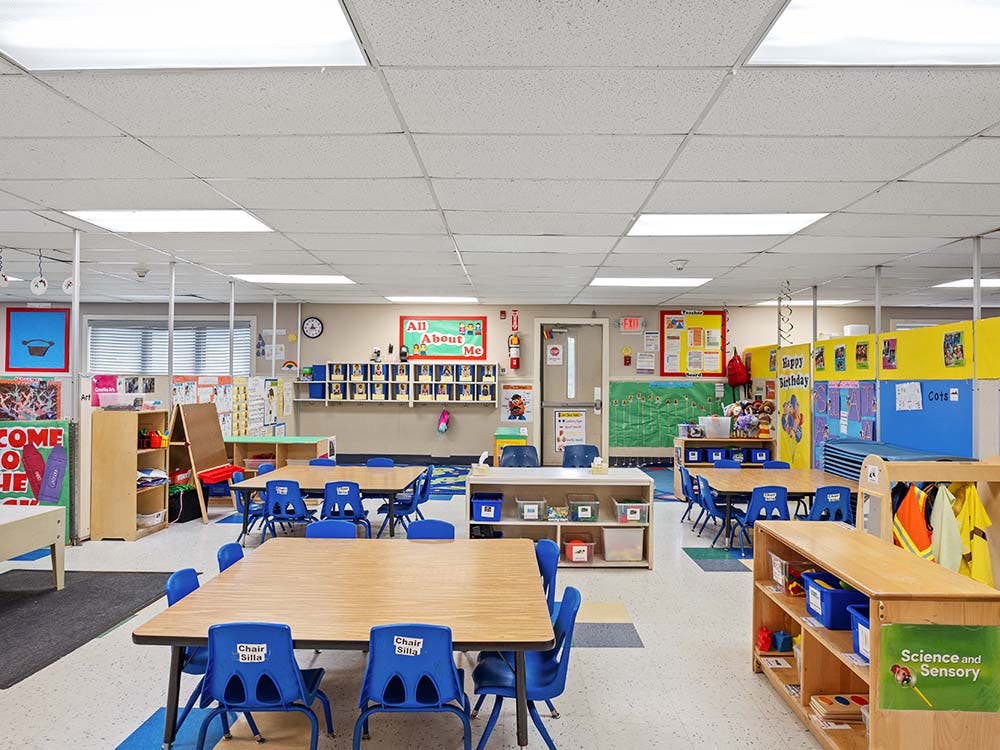 Empty classroom with small tables and chairs, and colorful decorations on walls