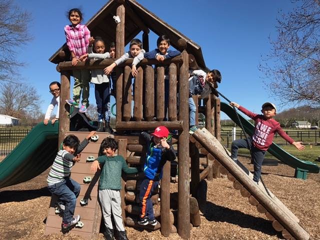 Children playing on a wooden playground structure with slides