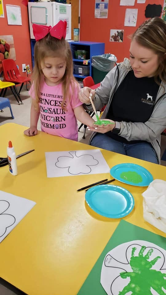 Adult and child painting a craft in a classroom