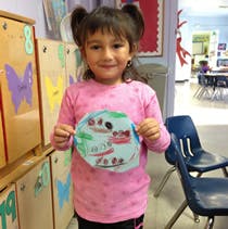 Child holding up a paper plate craft