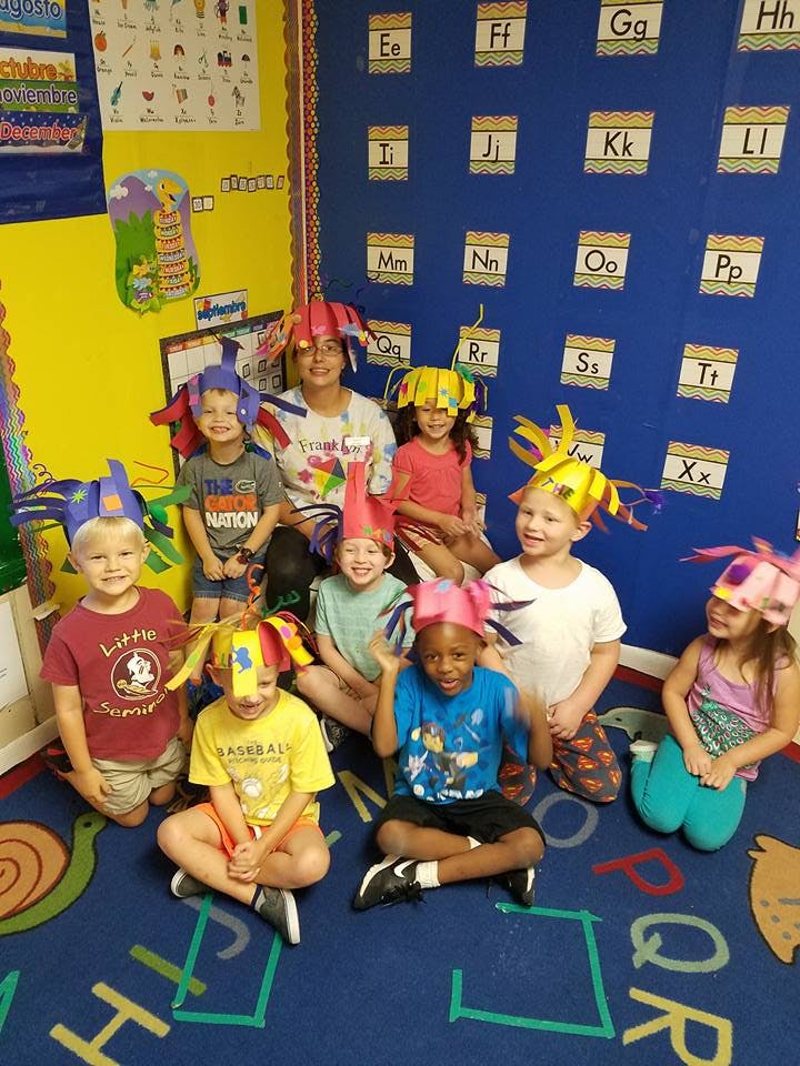 Adult and children wearing colorful hats in a classroom