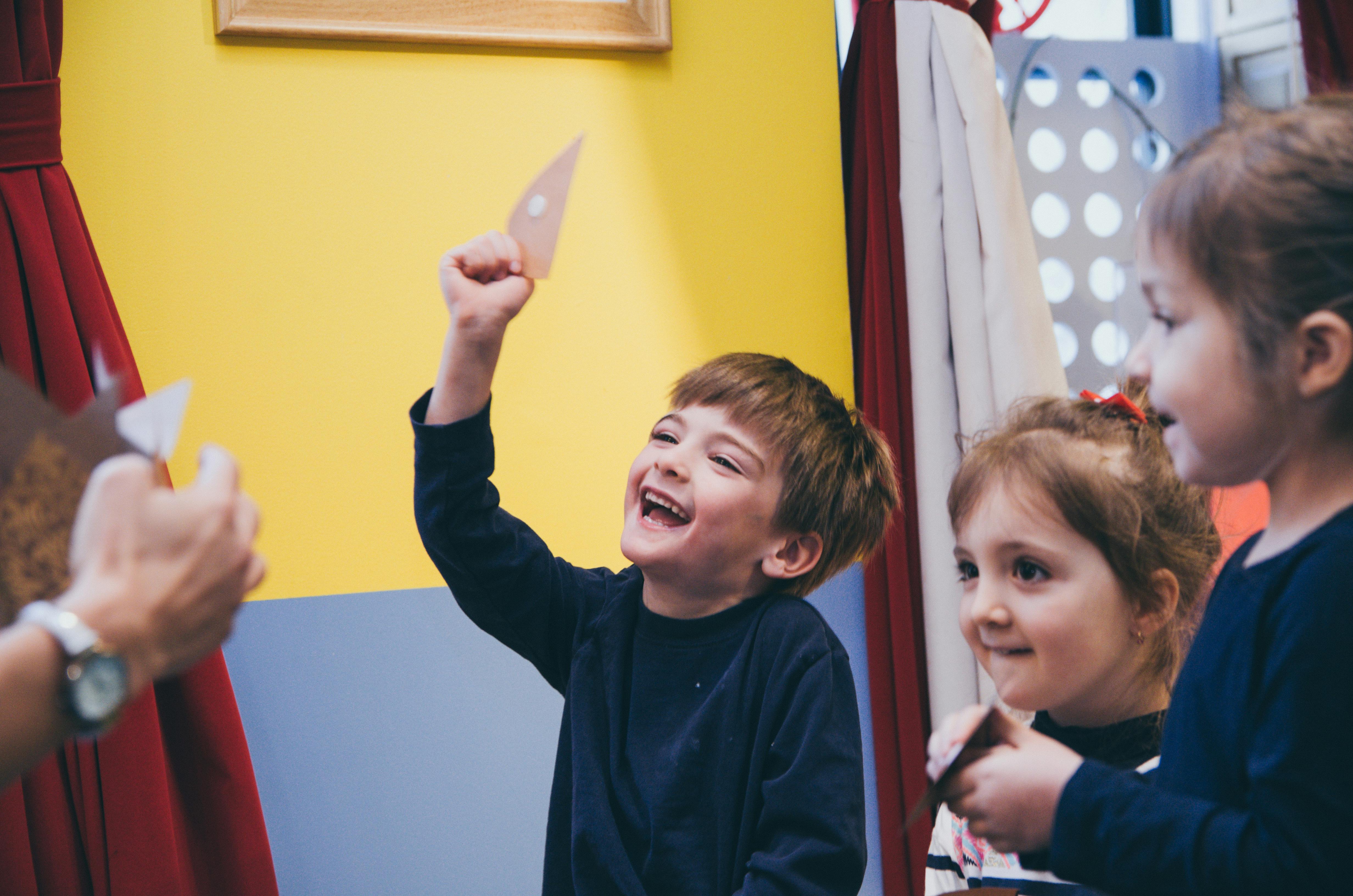 Child holding up a paper cutout with other children watching