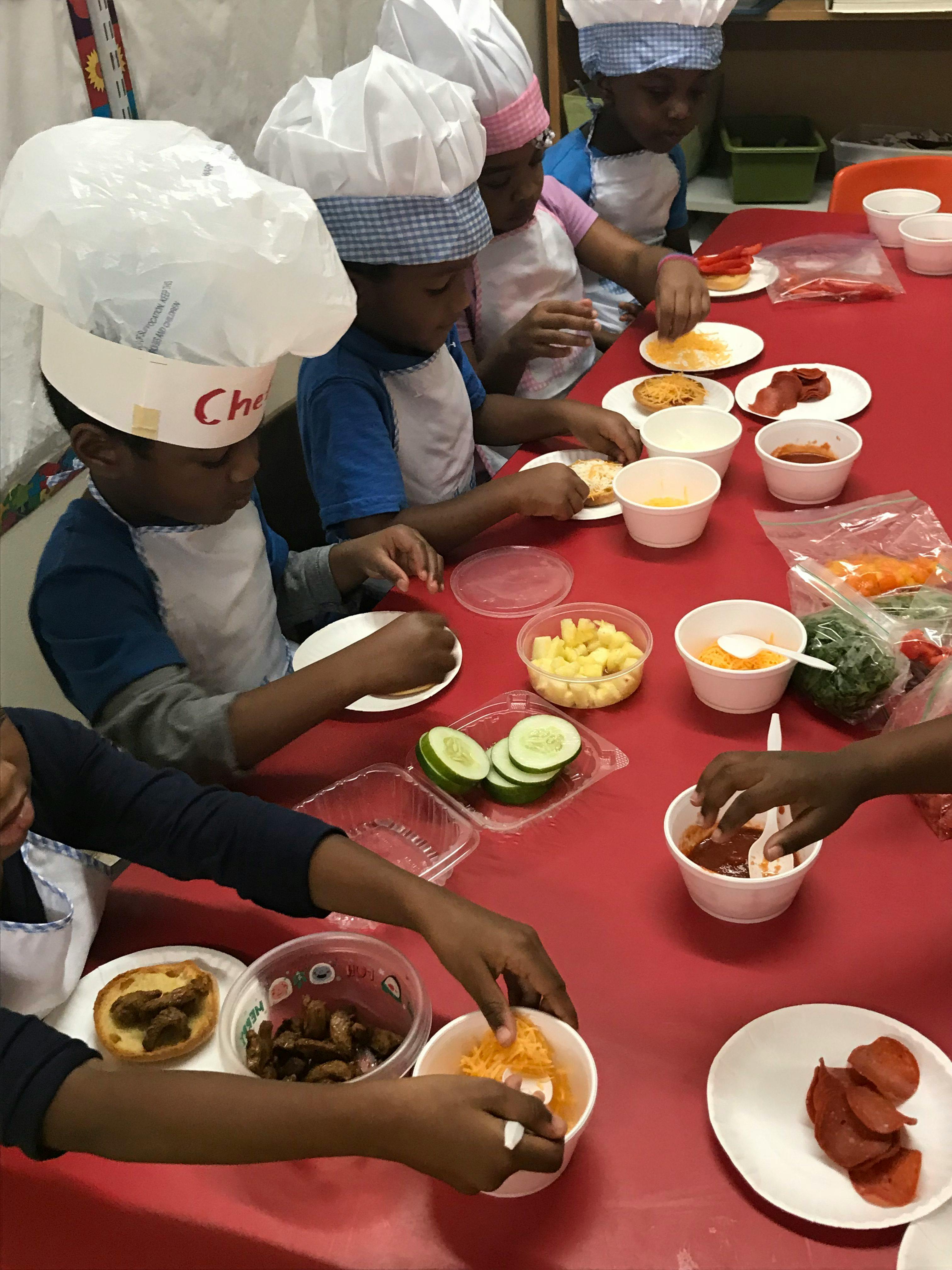 Children in chef hats preparing food at a table