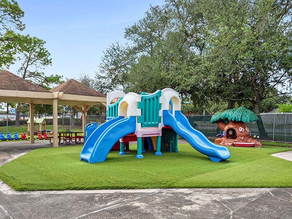 Empty playground with two blue slides and a tree playhouse