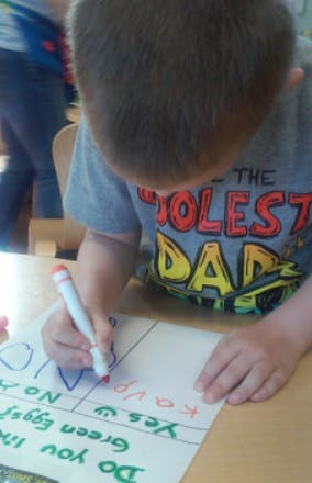 Child writing on paper with a marker