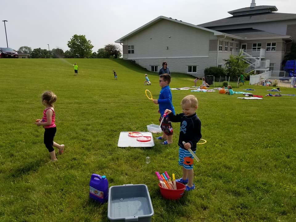 Children playing with bubble wands in a grassy field