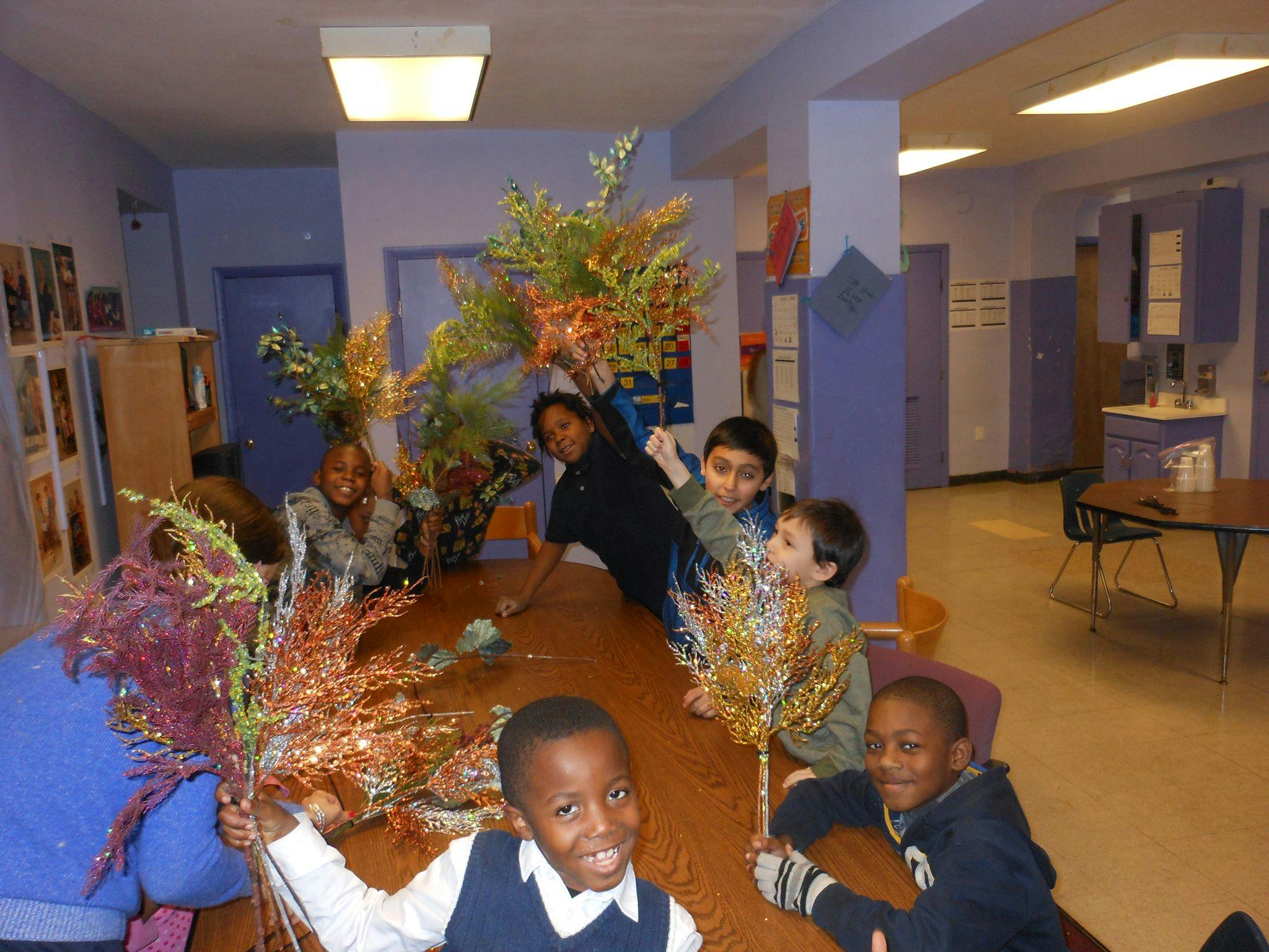 Children holding decorative branches around a table