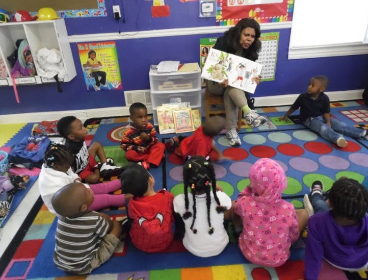 Person reading a book to children in a classroom