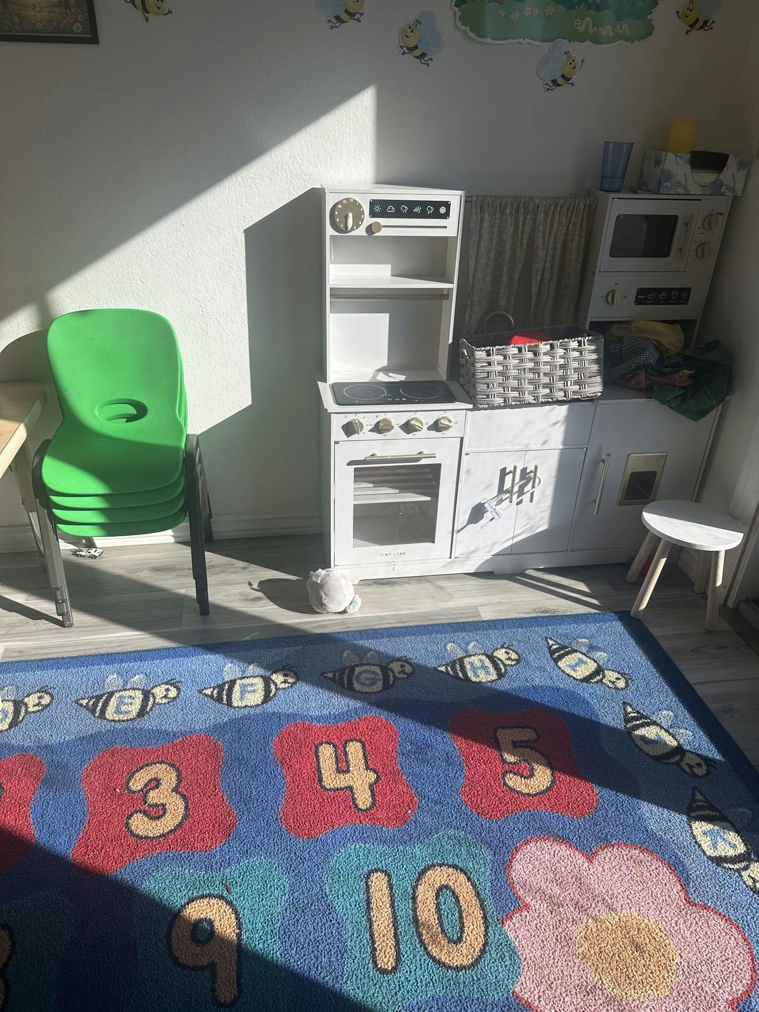 Play kitchen and chairs on a numbered educational rug in a playroom