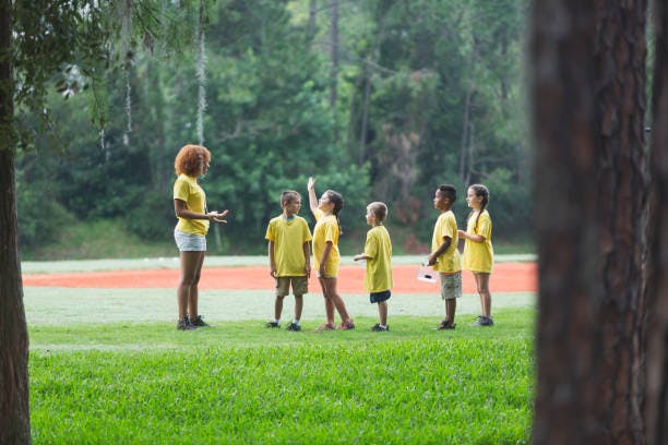 Person and children in yellow shirts on a grassy field